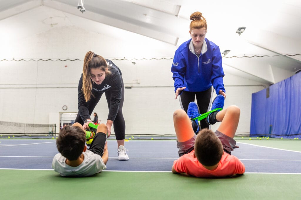 Two girls giving leg training to two boys at an institute